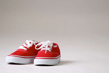 a pair of red shoes with white laces on a clean creme   white background isolated の写真素材