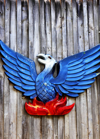 Red and blue stylised bird symbol hanging on fenceの写真素材