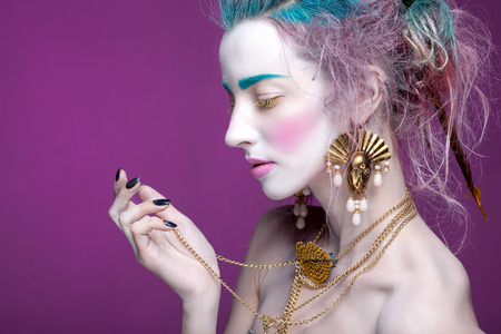 Creative portrait of young woman with artistic make-up. With bright colors in her hair and a white face.の写真素材