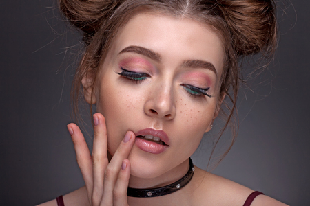Portrait of a beautiful girl with a beautiful make-up on a gray background. The youth style.の写真素材