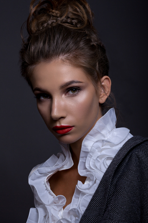 Portrait of a beautiful girl in a classic image. With a creative hairstyle and a bright make-up on a gray background. Gray jacket overweighedの写真素材