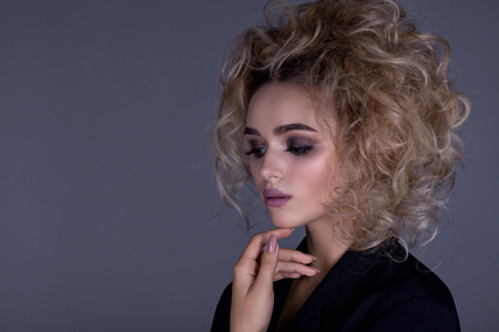 Portrait of a beautiful girl in a strict style, with a distinct look in a black jacket on a gray backgroundの写真素材