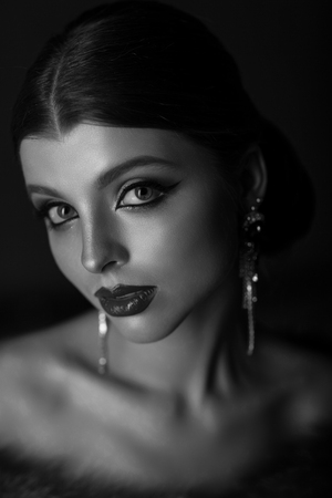 Black and white portrait of a beautiful teenage girl. With an aristocratic image, a strict hairstyle and long earrings.の写真素材