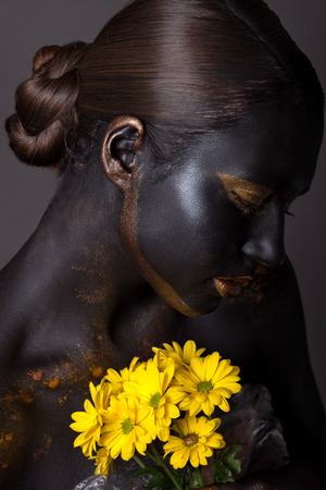 Portrait of a beautiful girl with a creative make-up, close-up. With yellow flowers.の写真素材