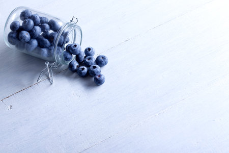 Beautiful blueberries in a glass jar. Against the background of white boards.