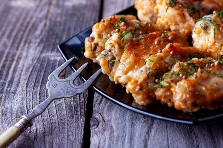 Spiced fried chicken. On a black plate, against a background of gray aged boards.の写真素材