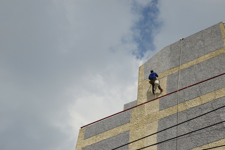 A man is risky painting high wall.の写真素材