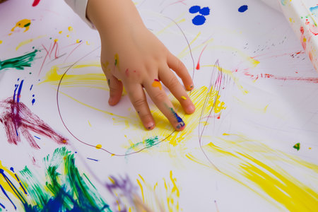 child's hand on a sheet of paper with a child's drawingの素材