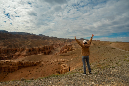 tourist raised her hands up and looks at the beautiful mountains canyons, rear view