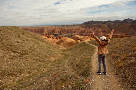 female tourist on the trail looking at the beautiful canyon mountains and cloudy skyの写真素材