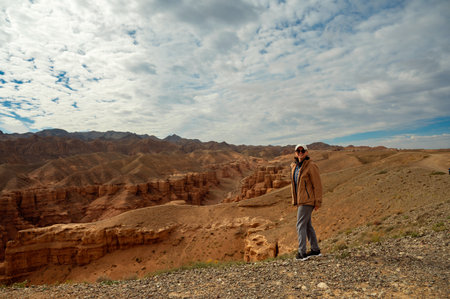 female tourist looks at the camera and smiles against the backdrop of beautiful mountains canyonsの写真素材
