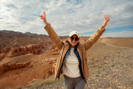 tourist raised her hands up and smiles against the backdrop of beautiful mountains canyonsの写真素材