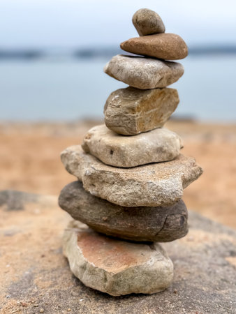Stacked stones on a tranquil lake shore, symbolizing balance, peace, and connection with natureの写真素材