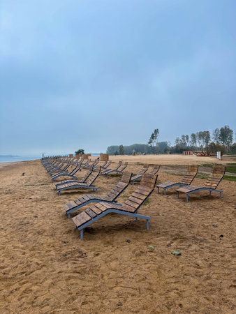 Empty wooden loungers on a sandy lakeside beach, peaceful scene marking the quiet end of the holiday seasonの写真素材