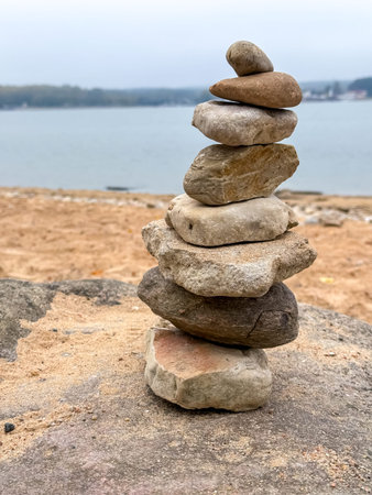 Stacked stones on a tranquil lake shore, symbolizing balance, peace, and connection with nature