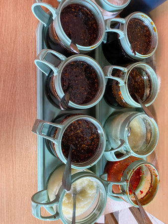 Tray with various Asian sauces in small containers on a wooden tableの写真素材