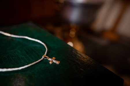 orthodox cross on ribbon on green bible close-up, bokeh