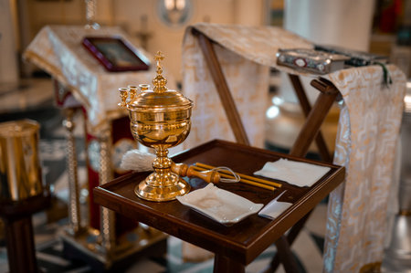 a small font, a cross and other church utensils on a table in an Orthodox church