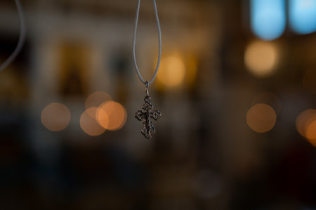 Orthodox cross pendant on a rope with soft bokeh background, symbol of faith and spiritual devotion in gentle lightの写真素材
