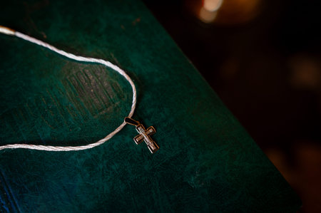 orthodox cross on ribbon on green bible close-up, bokeh