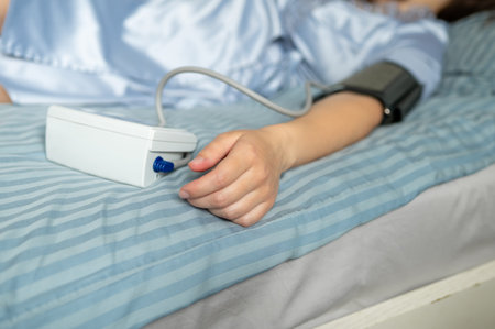 Close-up of digital blood pressure monitor and female hand during health measurement, medical...