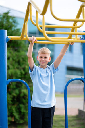Focused blond boy hangs on horizontal bars during outdoor workout, building strength and having fun...