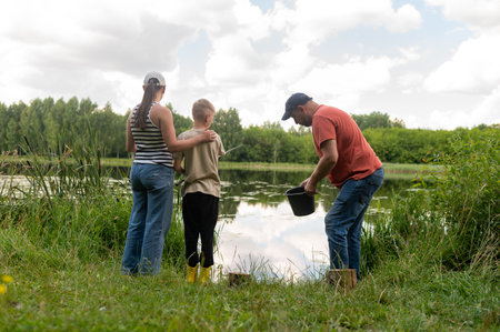 Family with teenage son fishing at lake, rear view of parents and child enjoying summer day