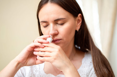 Young woman using nasal spray for relief from allergies or congestion, concept: at-home treatment