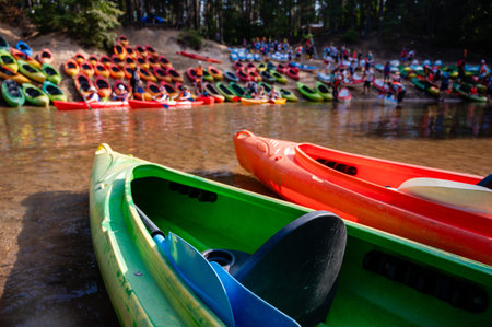 River shore with numerous kayaks on both banks, organized at a kayak base, prepared for summer rafting adventure, outdoors, water sport, natureの写真素材