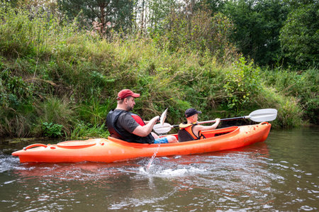 Father and son kayaking on river, spending quality family time, enjoying outdoor activity, summer...