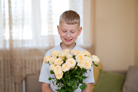 Teen boy holds a vibrant yellow rose bouquet, ready to gift his mother, celebrating love, gratitude, and family bonds on Mother's Dayの写真素材