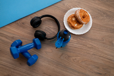Fitness equipment with dumbbells, water bottle, cookies on yoga mat at home, concept of healthy lifestyle and online workoutの写真素材