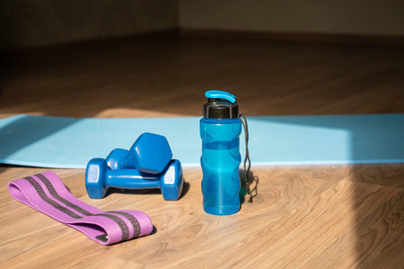 Dumbbells resistance band and water bottle placed on yoga mat on the floor at home, concept of fitness training and healthy lifestyleの写真素材