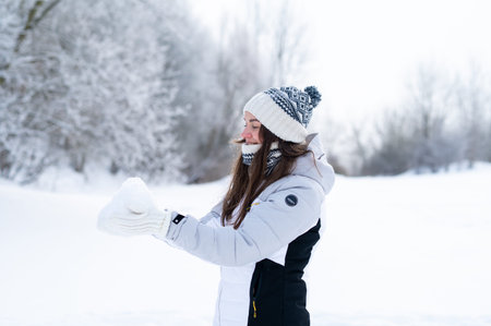 Young woman enjoying a peaceful winter walk in snowy park. Seasonal outdoor lifestyle, cold weather, calm mood and nature leisureの写真素材