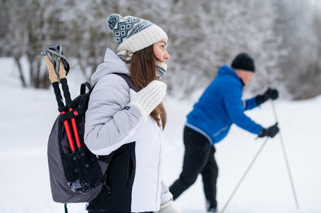 Young woman with backpack walking in snowy winter park, active lifestyle and outdoor recreationの写真素材