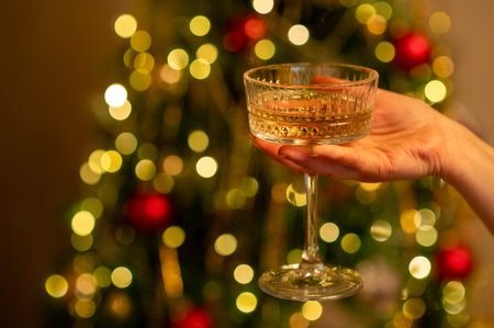 A close up shot of a female hand holding an elegant crystal champagne saucer filled with sparkling...