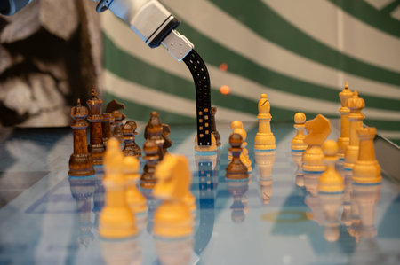 A close up shot of a high tech industrial robot manipulator moving a chess figure on a glowing blue touch display. Concept of artificial intelligence machine learning and future technology trendsの写真素材