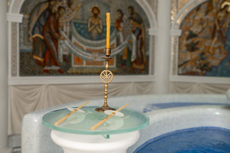 A close up shot of a brass candle holder with a Christogram monogram during a baptism ceremony....