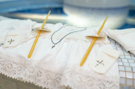Traditional christening accessories for newborn baby including embroidered gown candles and crucifix...