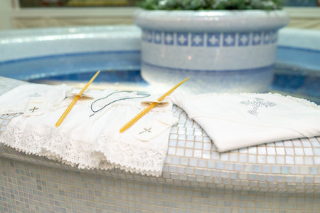 Traditional christening accessories for newborn baby including embroidered gown candles and crucifix...