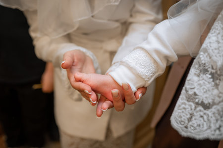 Tender moment of a parent gently touching small baby foot in white embroidered outfit conceptual...