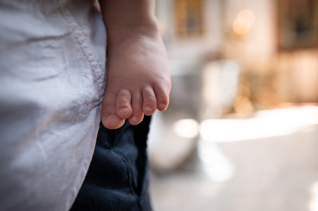 Tender moment of infant bare leg and tiny toes in focus with parent standing on background...