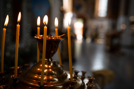 Close up of flickering candle fire on golden metal stand with shallow depth of field elegant home...