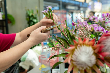 Close up of a flower shop worker using a vintage style secateur to cut small violet statice blossoms...