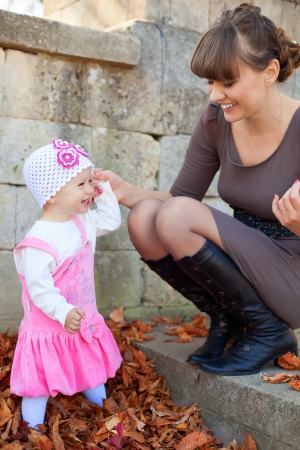 Family portrait cute little girl and cheerful mom  Posing in a park on a background of autumn leaves and bright colors の写真素材