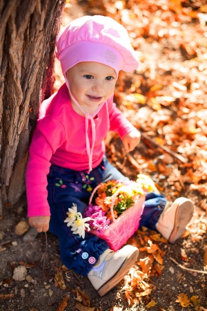 Portrait of a cute little baby posing in autumn park against fallen yellow leaves  
の写真素材