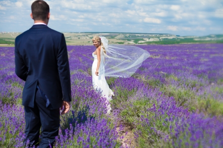 A young couple in love bride and groom, wedding day in summer  Enjoy a moment of happiness and love in a lavender field  Bride in a luxurious wedding dress on a background bright blue sky with clouds の写真素材