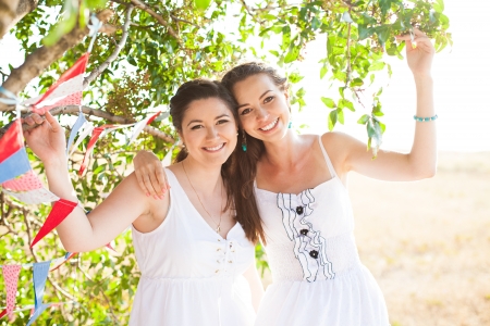Two young beautiful girlfriends resting under a tree in the heat of summer の写真素材