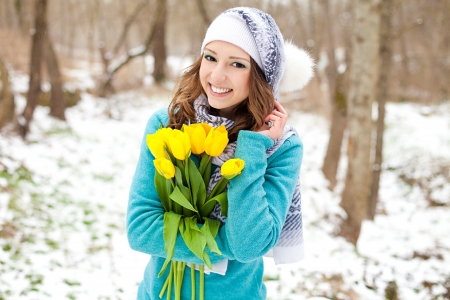 Portrait of a beautiful young girl with a bouquet of yellow tulips in the park の写真素材