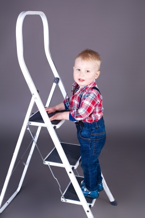 A little boy on a ladder in the studio on a gray background の写真素材